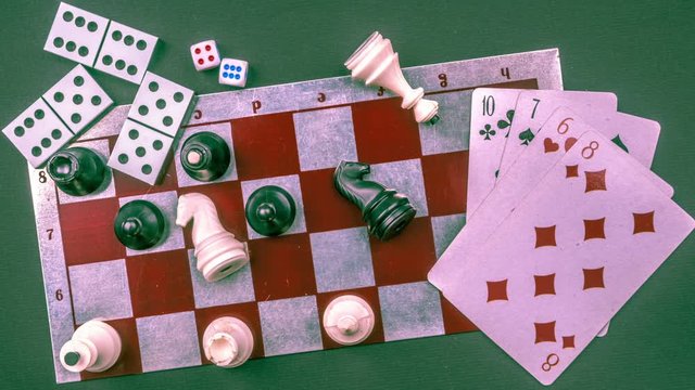 Stop motion animation of various board games and figurines over checkers board and dark background. Metaphor for gaming and gambling.