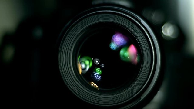 Camera lens with light sources reflecting and illuminating rotation. Shot at high speed 240fps.