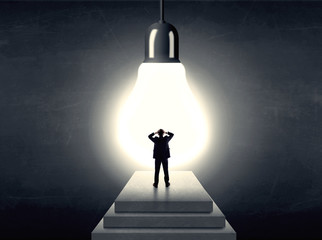Man standing on a step in front of a huge light bulb