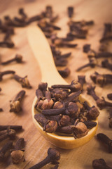 Vintage photo, Heap of cloves with wooden spoon on table, seasoning for cooking