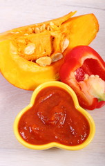 Sauce of pumpkin in glass bowl and ingredients on wooden table