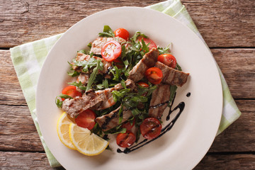 Straccetti salad with grilled beef, arugula and tomatoes close-up. Horizontal top view
