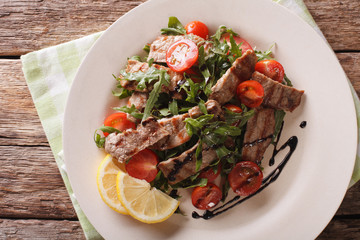 Warm salad of grilled beef with arugula and tomatoes close-up. horizontal top view
