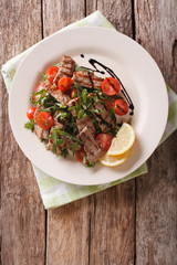 Straccetti Grilled beef with arugula and tomatoes close-up. Vertical top view
