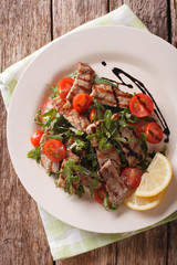 Straccetti salad with grilled beef, arugula and tomatoes close-up. Vertical top view
