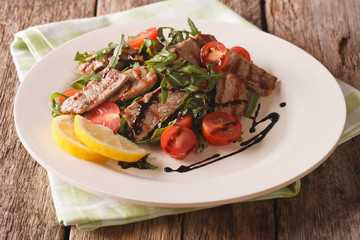Salad with grilled beef, arugula, tomatoes and balsamic vinegar close up. horizontal
