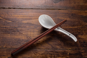 ceramic spoon and wooden shopstick on the wooden table top