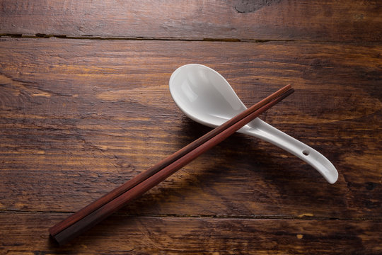 ceramic spoon and wooden shopstick on the wooden table top