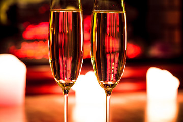 Two champagne glass with candles by the fireplace in the Christmas interior