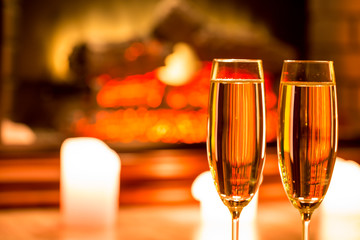 Two champagne glass with candles by the fireplace in the Christmas interior