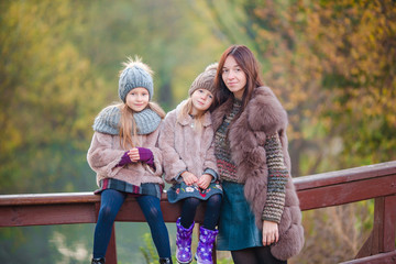 Adorable little girls and young mother in autumn park outdoors