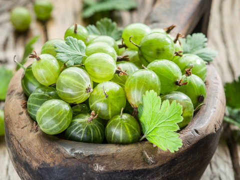 Gooseberries in the wooden bowl on the table.