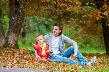 Adorable little girl with father in beautiful autumn park outdoors. Happy family enjoy their weekend outdoors
