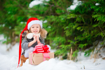 Adorable little gnome with Christmas box gift in winter outdoors on Xmas eve