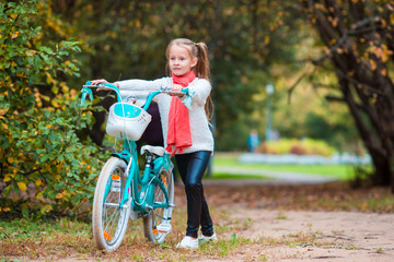 Adorable girl riding a bike at beautiful autumn day outdoors