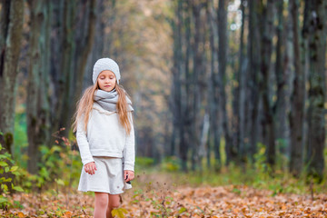 Adorable little girl outdoors at beautiful warm day in autumn park