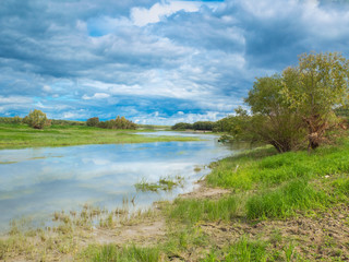 Fototapeta na wymiar Picturesque countryside landscape with cloud and small river and green grass. Natural scene. Nature.