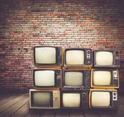 Antique and vintage style photo. retro televisions pile on floor in old room.