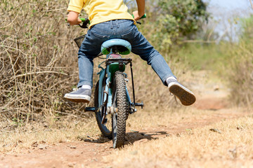 Little boy ride bicycle on the rock road.
