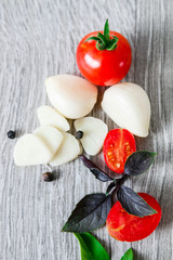 Close up of cherry tomatoes, garlic and fresh basil on grey wooden  background. Frame. Copy space.