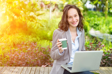 Young attractive business woman working at the park during a pau