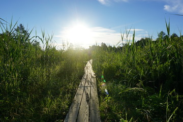 Backlit sunrise image of man running on mountain boardwalk trail 