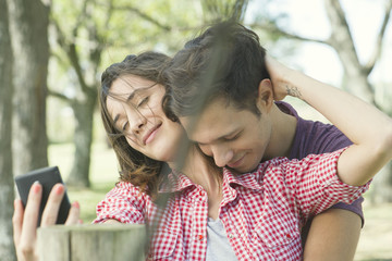 Couple embracing outdoors, posing for a selfie