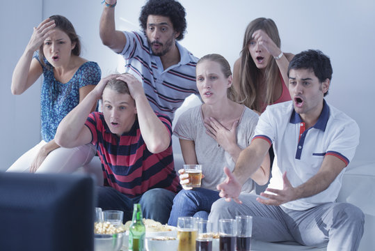Friends watching sports match on television together express disappointment at team's performance