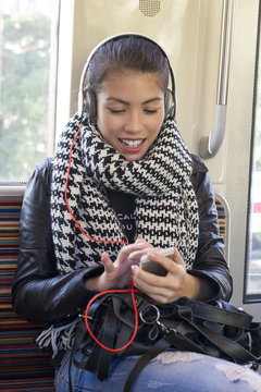 Young woman using smartphone on subway train