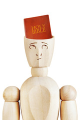 Holy Bible in the human head. Religious mind. Abstract image with a wooden puppet