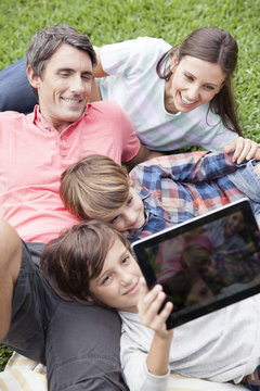 Boy photographing family with digital tablet camera