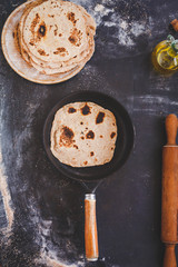 Fresh cooked arab flatbread in cast-iron pan on a dark rustic table.