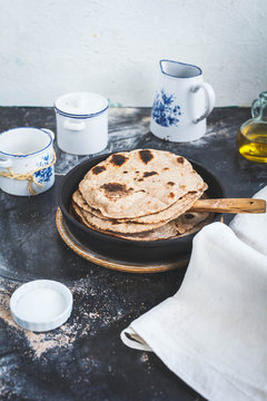 Fresh cooked arab flatbread in cast-iron pan on a dark rustic table.