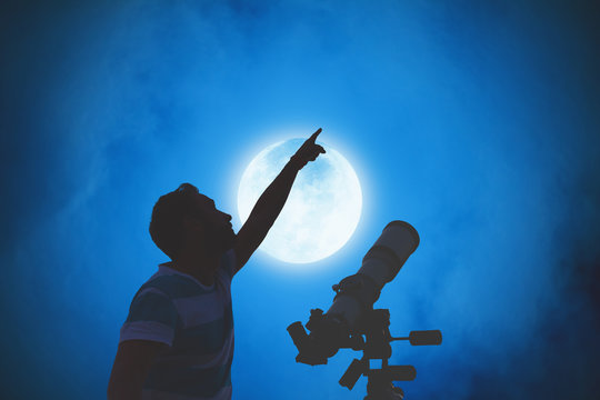 Man looking at the night sky with telescope beside him.