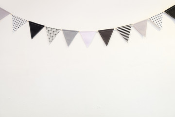 Fototapeta premium Small black white triangle shape flag hanging curve down plaster wall on white background