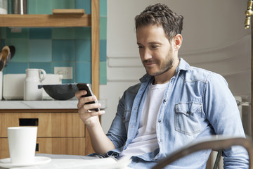 Man reading news on smartphone while having breakfast