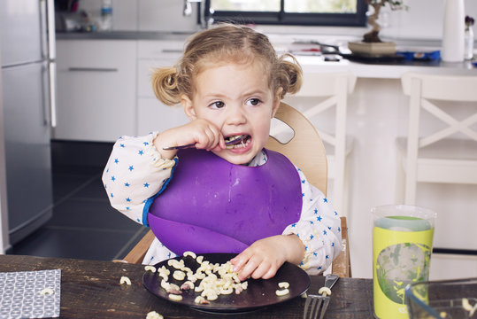 Girl eating pasta on dining table