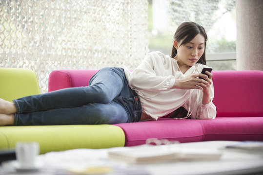 Woman relaxing at home with smartphone