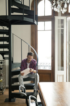 Man Sitting On Staircase Opening Package