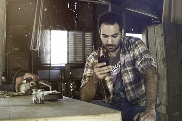 Man using smartphone to access internet and learn how to repair broken equipment