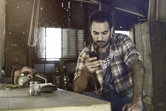 Man using smartphone to access internet and learn how to repair broken equipment