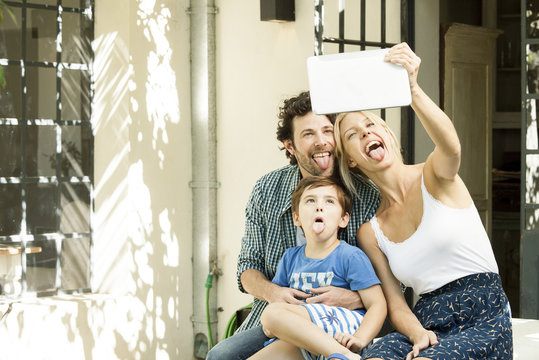 Family with one child posing for selfie taken with digital tablet