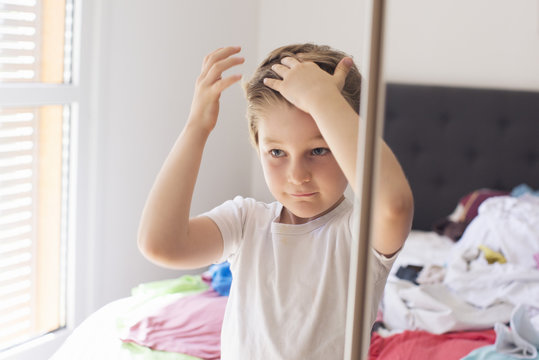 Boy fixing hair in front of mirror