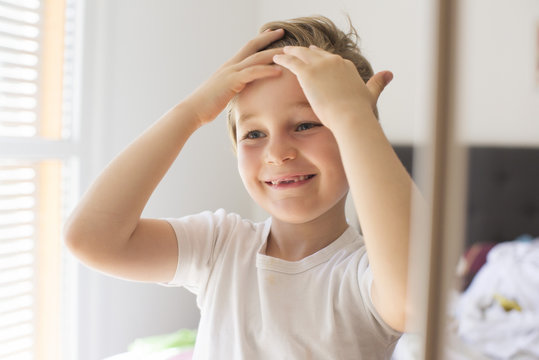 Boy fixing hair in front of mirror
