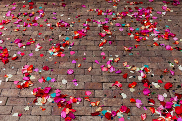 Red and pink rose petals scattered on stone sidewalk