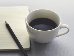 Coffee in white cup with Journal book and pencil
