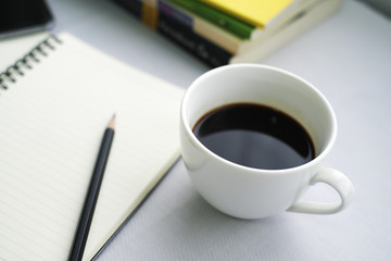 Obraz na płótnie Canvas Coffee in white cup with Journal book and pencil