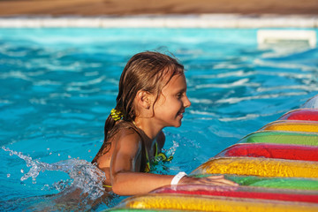 Happy girl playing in blue water of swimming pool.