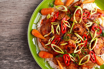 takeawy classic pork on rice with fried in sticky souce carrots, sprinkle of chillie and spring onion.