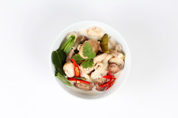 Chicken and galangal in coconut milk soup and herb on white background. Top view